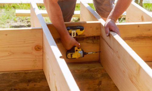 Full length of carpenter drilling wood at construction patio Full length of carpenter drilling wood at construction patio