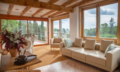 Wooden Door and Frames Elegant farmhouse second living area with sofas and easy chairs and patio doors on to upper terrace